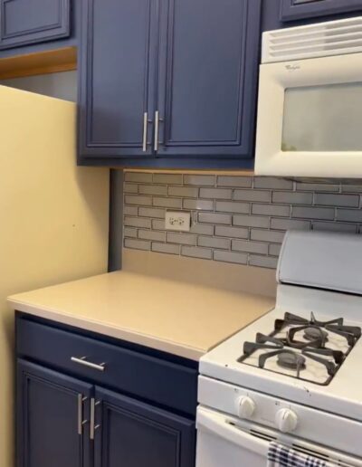 A kitchen with blue cabinets and white appliances.