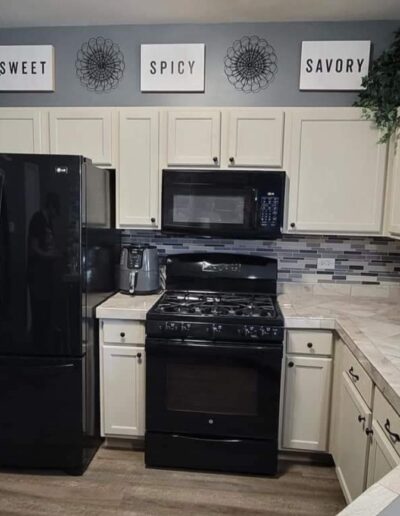 A kitchen with black appliances and white cabinets.