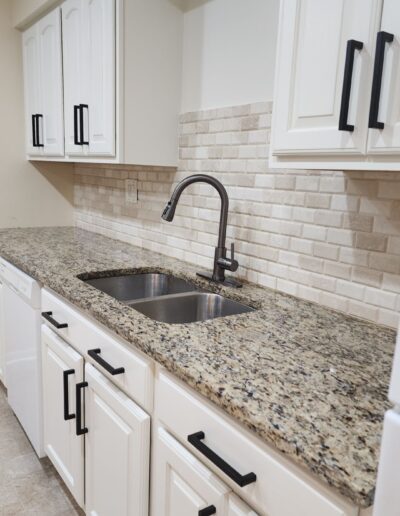 A kitchen with white cabinets and granite counter tops.