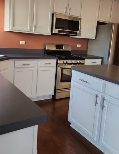 A kitchen with white cabinets and gray counter tops.