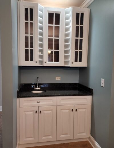 A kitchen with white cabinets and a black counter top.