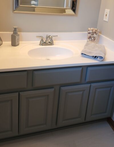 A bathroom vanity with gray cabinets and a mirror.