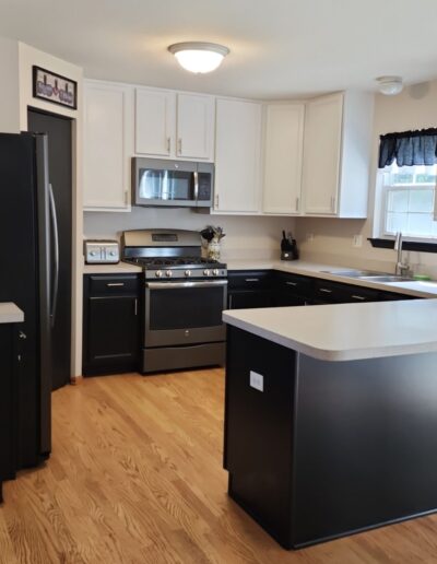 A kitchen with white cabinets and black appliances.