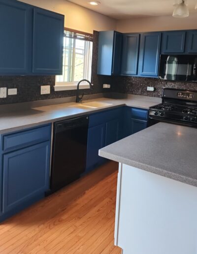 A kitchen with blue cabinets and stainless steel appliances.