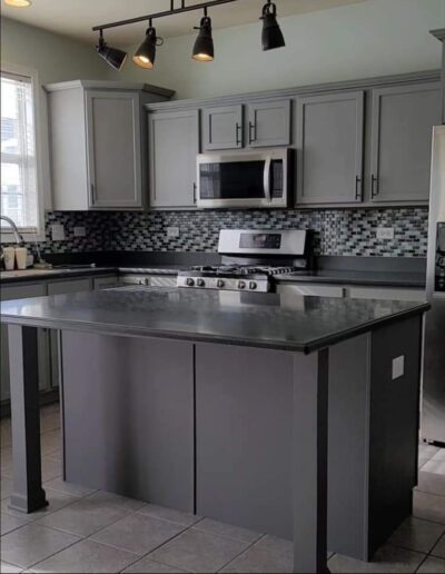 A kitchen with gray cabinets and a gray island.