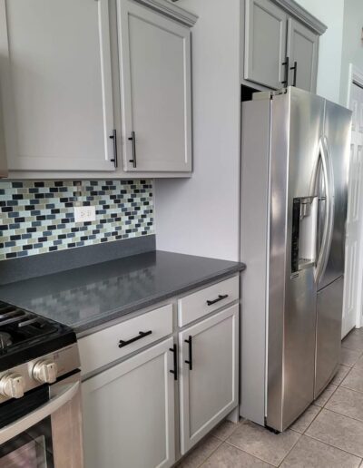 A kitchen with gray cabinets and stainless steel appliances.