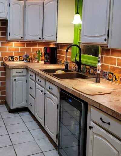 A kitchen with white cabinets and tiled floors.