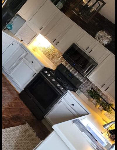 A kitchen with white cabinets and black appliances.