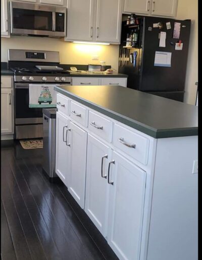 A kitchen with white cabinets and black counter tops.