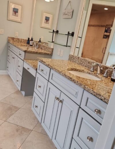 A bathroom with white cabinets and granite counter tops.