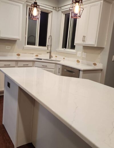 A kitchen with white cabinets and counter tops.