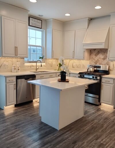 A white kitchen with hardwood floors and stainless steel appliances.