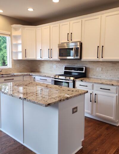 A kitchen with white cabinets and granite counter tops.