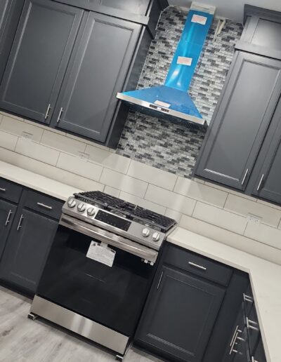 A kitchen with gray cabinets and a blue hood.