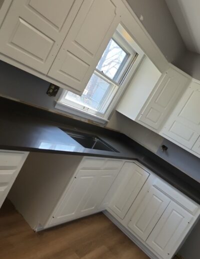 A kitchen with white cabinets and a black counter top.