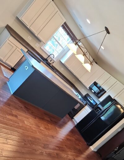 A kitchen with white cabinets and hardwood floors.