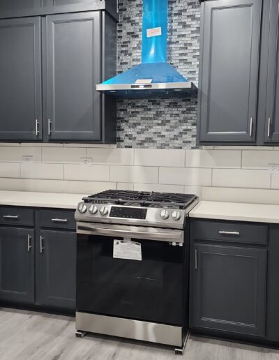 A kitchen with gray cabinets and a blue stove top.