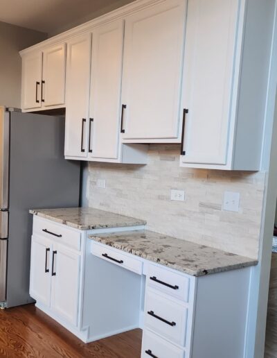 A kitchen with white cabinets and a refrigerator.