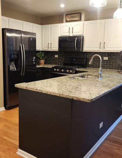 A kitchen with black cabinets and granite counter tops.