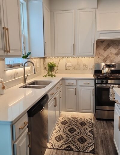 A kitchen with white cabinets and hardwood floors.