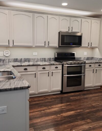 A white kitchen with wood floors and stainless steel appliances.