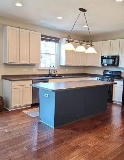 A kitchen with hardwood floors and white cabinets.