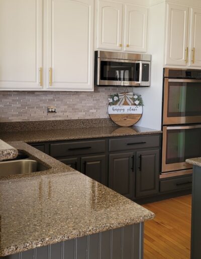 A kitchen with white cabinets and granite counter tops.