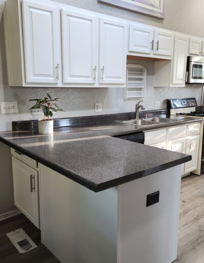 A kitchen with white cabinets and counter tops.