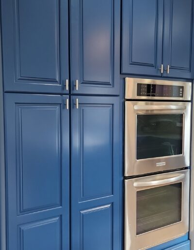 A kitchen with blue cabinets and stainless steel appliances.