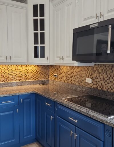 A kitchen with blue cabinets and white counter tops.