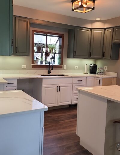 A kitchen with white cabinets and green counter tops.