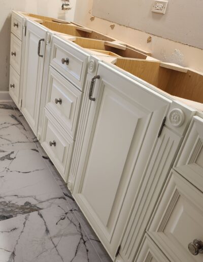 A bathroom with white cabinets and marble counter tops.