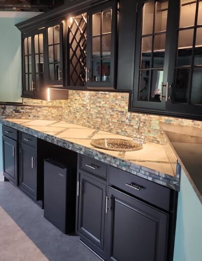 A kitchen with black cabinets and granite counter tops.