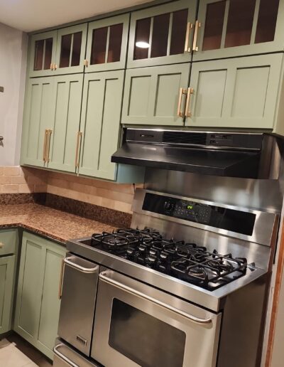 A kitchen with green cabinets and stainless steel appliances.