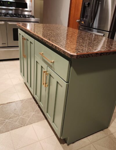 A kitchen with green cabinets and stainless steel appliances.