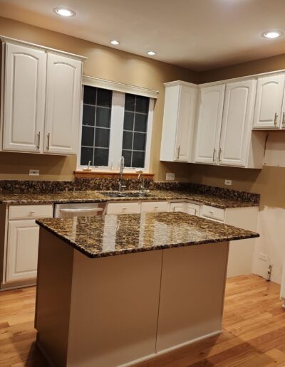 A kitchen with white cabinets and granite counter tops.