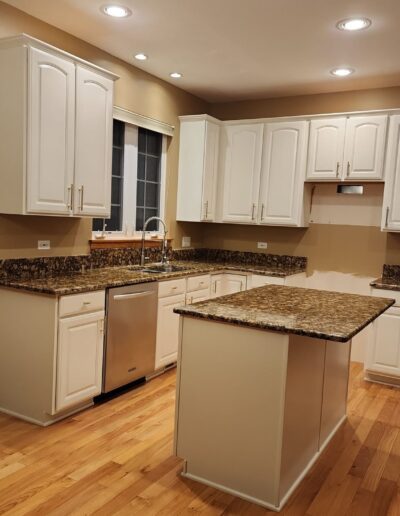 A kitchen with white cabinets and hardwood floors.