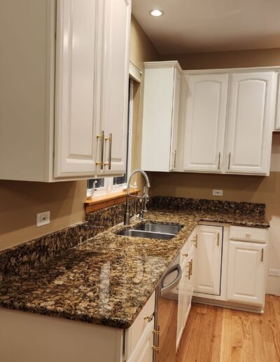 A kitchen with white cabinets and granite counter tops.