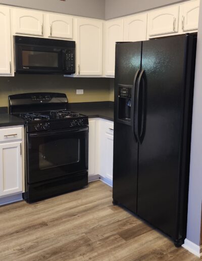 A kitchen with black appliances and wood floors.