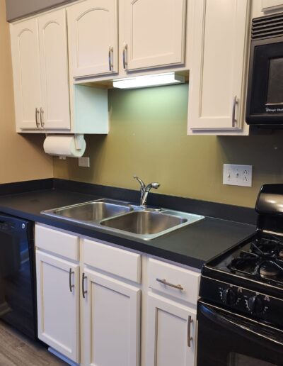 A kitchen with white cabinets and black appliances.