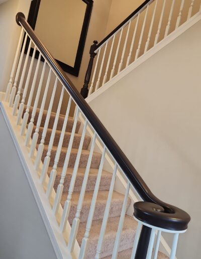 A staircase with a white railing and black railing.