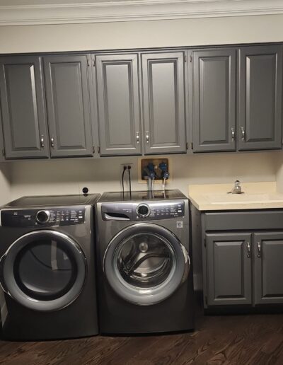 A laundry room with gray cabinets and a washer and dryer.