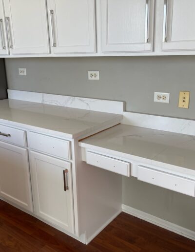 A kitchen with white cabinets and a white counter top.